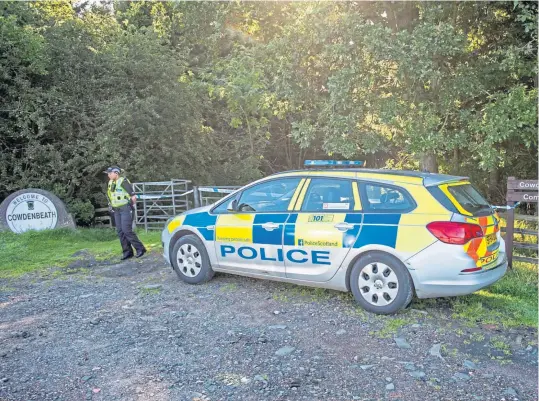  ?? Picture: Wullie Marr. ?? A police officer stands guard at the entrance to Woodend Community Woodland on the outskirts of Cowdenbeat­h where the 23-year-old woman was found critically injured.