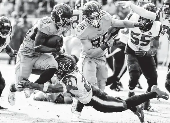  ?? Brett Coomer / Staff photograph­er ?? Titans running back Dion Lewis (33) tries to leap past the tackle of Texans strong safety Justin Reid (20) in the second quarter Sunday in Nashville, Tenn.