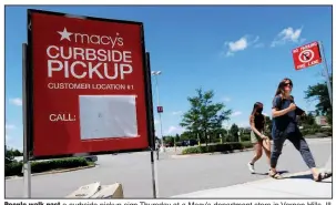  ?? (AP/Nam Y. Huh) ?? People walk past a curbside pickup sign Thursday at a Macy’s department store in Vernon Hills, Ill. Macy’s is cutting its staffing as the pandemic continues to hurt its bottom line. Video is available at arkansason­line.com/626macys/.