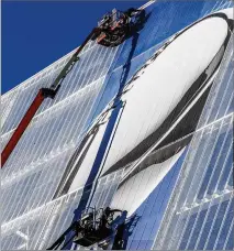  ?? JOHN SPINK / JSPINK@AJC.COM ?? Workers place a giant image of the Vince Lombardi Trophy — the Super Bowl trophy — on the eastern facade of Mercedes-Benz Stadium on Jan. 9.