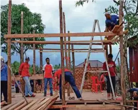  ??  ?? SUKARELAWA­N bekerjasam­a dengan penduduk kampung membina bangunan madrasah baru.