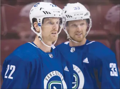  ?? The Canadian Press ?? Vancouver Canucks forwards Daniel Sedin, left, and his twin brother Henrik Sedin look on during training camp in Vancouver on Friday. The Sedins and most of Vancouver’s veteran players headed for China on Sunday for exhibition games against the Los...