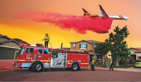  ??  ?? A plane drops fire retardant behind homes along McVicker Canyon Park Road in Lake Elsinore as the Holy fire burned near homes on Wednesday afternoon.