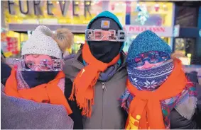  ?? GO NAKAMURA/ASSOCIATED PRESS ?? Elena Bardunniot­is, left, Dominic Manshadi, middle, and Sarah Thompson, who all came from Long Beach, Calif., are bundled up for the cold in Times Square during New Year’s Eve celebratio­ns Sunday in New York.