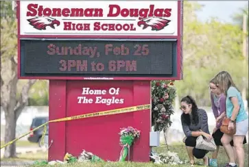  ?? David Santiago Miami Herald ?? MOURNERS in February visit a memorial for the victims of the shooting at Marjory Stoneman Douglas High School in Parkland, Fla. A 19-year-old suspect is accused of using a semiautoma­tic rifle to kill 17 people.