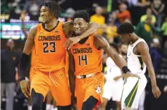  ?? Waco TribuneHer­ald via AP ?? ■ Oklahoma State forward Tyreek Smith, left, walks off with teammate guard Bryce Williams following their win over No. 1 Baylor in an NCAA basketball game Saturday in Waco, Texas. Leaving the court for Baylor is Adam Flagler, right.