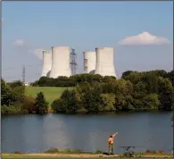  ?? (AP/Petr David Josek) ?? A man fishes with the towering Dukovany nuclear power plant in the background, in Dukovany, Czech Republic, in 2011.