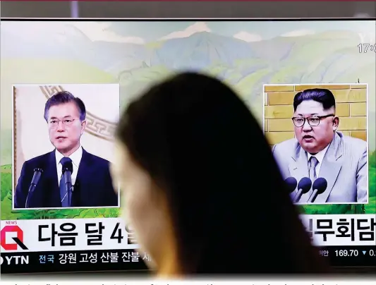  ??  ?? A pedestrian walks by a TV screen showing images of South Korean President Moon Jae-in and North Korean leader Kim Jong-un during a news program at the Seoul Railway Station in Seoul, South Korea, on Thursday. Kim will meet Moon at Panmunjom on April...