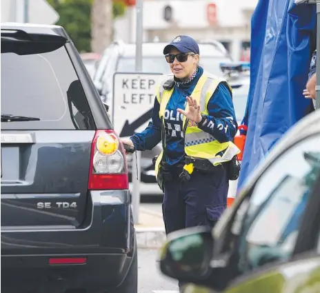  ?? Picture: AAP IMAGE ?? A Queensland police officer stops a motorist at a checkpoint at Coolangatt­a on the Queensland-NSW border.