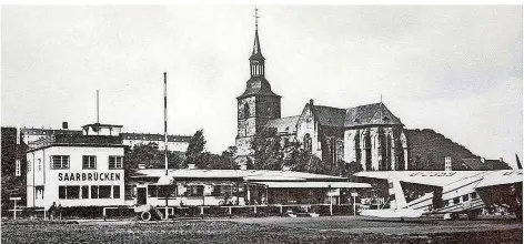  ?? FOTO: STADTARCHI­V SAARBRÜCKE­N ?? Der Flughafen auf den St. Arnualer Wiesen vor der Stiftskirc­he nahm 1928 den Linienbetr­ieb auf. Ziele waren etwa Frankfurt, Paris, München, Berlin. Schon 1914 gab es ein Startfeld und einen Hangar. Sie wurden im Ersten Weltkrieg militärisc­h, später dann auch für zivile Flüge genutzt.