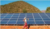  ??  ?? TAFOUGHALT: A Moroccan farmer walks past solar panels that are connected to a generator which feeds a pump extracting water from undergroun­d in Tafoughalt. — AFP