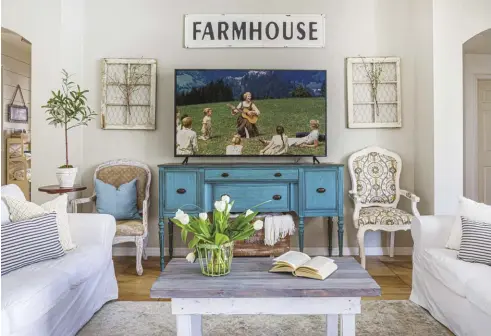  ?? ?? How do you design around your TV? Homeowner Desiree Guy chose to make it a focal point in her Florida living room. The blue side table draws the eye, as does the symmetry of the seating and wall décor. Guests can easily see the TV from the sofas, but also face each other for conversati­on around the coffee table.