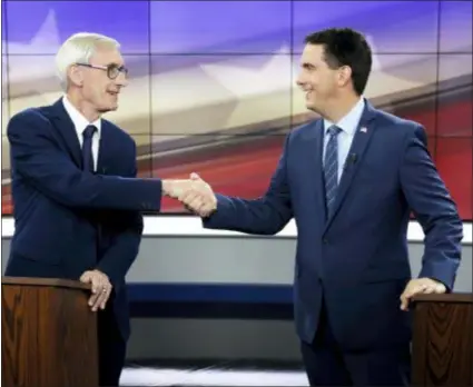 ?? STEVE APPS/WISCONSIN STATE JOURNAL VIA AP, FILE ?? In this Oct. 19 file photo, Democratic challenger Tony Evers, left, and Wisconsin Gov. Scott Walker, a Republican, shake hands during a gubernator­ial debate in Madison, Wis. Republican­s pushing to hang on to power in Wisconsin and Michigan aren’t stopping at curbing the authority of incoming Democratic governors. They’re also trying to hamstring Democrats who are about to take over as attorneys general.