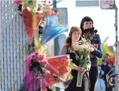  ?? ASSOCIATED PRESS ?? Well-wishers walk to place flowers at the scene of a deadly fire at a warehouse in Oakland, Calif., that was hosting a late-night dance party.