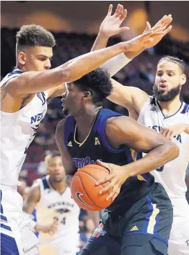  ?? JOHN LOCHER/ASSOCIATED PRESS ?? Nevada defenders Trey Porter, left, and Caleb Martin double-team Tulsa’s Simon Falokun during the sixth-ranked Wolf Pack’s 96-86 victory on Thursday in Las Vegas, Nev.