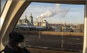  ??  ?? A woman rides on a tram Friday with the Kremlin in the background. Turnout to get the Russian covid-19 vaccine has been less than enthusiast­ic.
(AP/Pavel Golovkin)