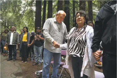  ?? Photos by Patrick Tehan / Special to The Chronicle ?? Valentin Lopez, chair of the Amah Mutsun Tribal Band (center), and tribal band member Clora Hanley pray before the removal of a historic mission bell marker from the UC Santa Cruz campus.