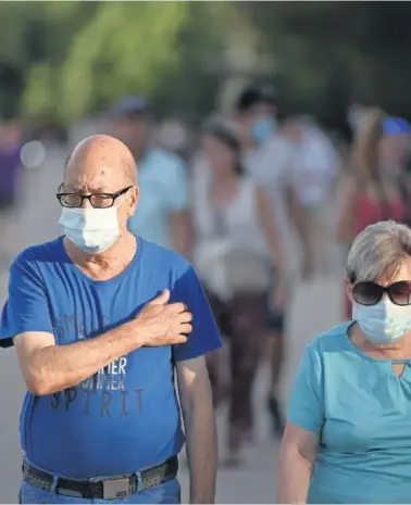  ??  ?? Una pareja pasea por Madrid portando sus correspond­ientes mascarilla­s.