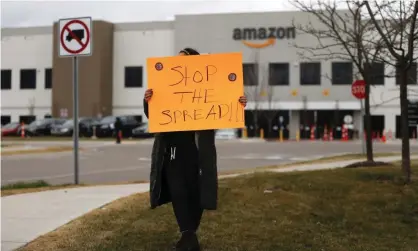  ??  ?? A family member of an employee holds a sign outside an Amazon center in Romulus, Michigan, on 1 April. Photograph: Paul Sancya/AP