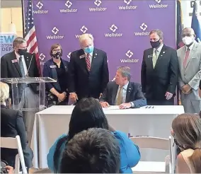  ?? Contribute­d, File ?? Sen. Chuck Hufstetler, right, and Rep. Lee Hawkins flank a seated Gov. Brian Kemp at a ceremony on July 16 at Wellstar Kennestone Hospital where Kemp signed into law their legislatio­n addressing the issue of surprise medical bills.