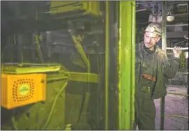  ??  ?? A Bosnian coal miner checks equipment in an undergroun­d tunnel.