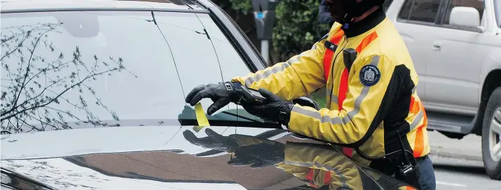  ?? STEVE BOSCH/PNG FILES ?? A Vancouver parking enforcemen­t officer places a ticket on a car’s windshield. The city says less than five per cent of tickets are overturned.