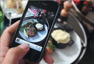  ?? ANA AREVALO / AGENCE FRANCE-PRESSE ?? A man takes a cellphone snapshot of his meal to share it on the “Food Reporters” network during lunch at a Paris restaurant.