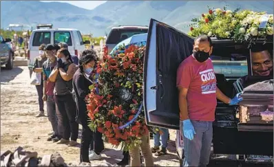  ??  ?? A FUNERAL HOME worker, above, prepares to unload a casket at the Tijuana cemetery. To fight the coronaviru­s, the city government limits how many family members are allowed to attend a funeral.