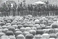  ?? JACK GUEZ, AFP/GETTY IMAGES ?? Israeli riot police keep watch as Palestinia­n worshipers pray outside Jerusalem’s Old City on Friday after days of protests.