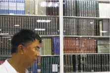  ?? Andy Wong / Associated Press ?? A Chinese man walks by a cabinets displaying Chinese encycloped­ias at a book store in Beijing.