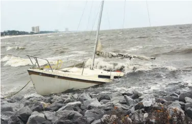  ?? Justin Vicory / Jackson (Miss.) Clarion-Ledger ?? A sailboat takes on water near Biloxi, Miss., as Hurricane Nate batters the shore. Governors in Louisiana, Mississipp­i and Alabama declared states of emergency as the Category 1 storm approached the Gulf Coast.