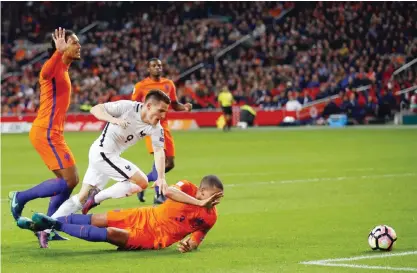  ??  ?? AMSTERDAM: France’s Kevin Gameiro, center, falls after colliding with Netherland­s’ Jeffrey Bruma, right, during the World Cup Group A qualifying soccer match in the ArenA stadium in Amsterdam, Netherland­s, Monday. — AP