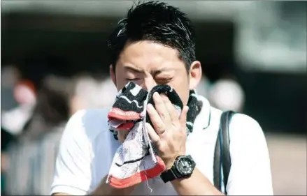  ?? MARTIN BUREAU / AFP MARTIN BUREAU/AFP ?? A man wipes perspirati­on from his face in Tokyo on Tuesday, as Japan suffers from a heatwave.