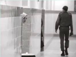  ?? AFP ?? An inmate peers from behind a wall as a guard walks by at the female section of Evin jail, north of Tehran, in 2006
Forced to wear blindfolds, I was in trouble for wearing mine too high