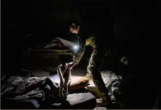  ?? Bernat Armangue / Associated Press ?? A Ukrainian serviceman pets a cat in a basement previously used by Russian soldiers as a temporary base in the village of Malaya Rohan, east Ukraine on Monday.