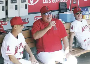  ??  ?? Mike Scioscia mientras conversaba el el dogout con el coach Dino Eber y otro integrante del staff en su último juego como manager de Anaheim.