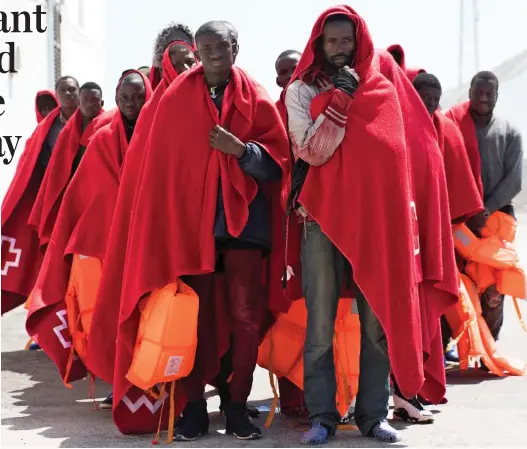  ??  ?? Ashore at last: In Red Cross blankets, some of 55 migrants rescued from a dinghy on Sunday set foot in Motril, southern Spain
