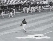  ?? JOHN MINCHILLO AP ?? Marlins center fielder Lewis Brinson walks away from home plate Thursday after placing a Black Lives Matter T-shirt as his teammates and the New York Mets walk off the field after deciding to postpone their game.