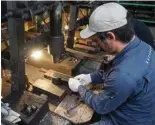  ?? ?? Knife maker Yoshihiro Yauji places a “santoku”, a multipurpo­se knife, under a spring hammer at the Takefu Knife Village in the town of Echizen, Fukui prefecture.