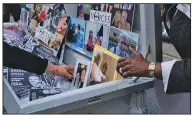  ?? (AP/Yuki Iwamura) ?? People look at pictures and leaflets Sunday during a protest in the Brooklyn borough of New York by families of covid-19 victims who have died in nursing homes during the pandemic.