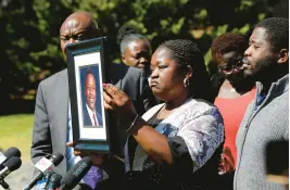  ?? DANIEL SANGJIB MIN/RICHMOND TIMES-DISPATCH ?? Caroline Ouko, mother of Irvo Otieno, holds a portrait of her son with attorney Ben Crump, left, and her older son, Leon Ochieng at the Dinwiddie Courthouse in Dinwiddie on March 16. She said Otieno, who died in a state mental hospital March 6, was “brilliant and creative and bright.”