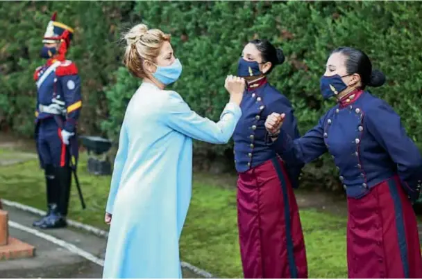  ??  ?? Fabiola saludó a las damas que forman parte del Regimiento de Granaderos con el codo y a con la distancia debida. Lució un peinado recogido en un chignon.