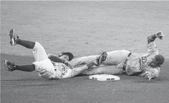  ?? Michael Ciaglo / Houston Chronicle ?? Second baseman Jose Altuve,left, dives to tag out Dodgers right fielder Yasiel Puig in the fourth inning. It was one of several stellar defensive plays by the Astros.