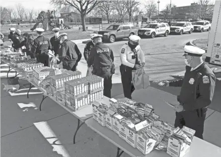  ?? FRED SQUILLANTE/COLUMBUS DISPATCH ?? Columbus police officers fill bags with Thanksgivi­ng meal items at the Douglas Recreation Center on Wednesday before heading to Rosewind Apartments, where residents were given turkey dinners.