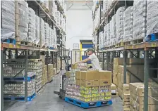  ?? Sue Ogrocki, The Associated Press ?? James Ambot stacks foods onto a pallet at the Regional Food Bank of Oklahoma on Thursday in Oklahoma City. The rush on grocery stores because of COVID-19 has put a bite into the budget at the food bank, which relies mostly on donations of overstock food items to redistribu­te to the needy.