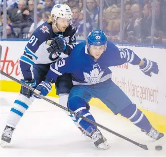  ??  ?? Maple Leafs defenceman Travis Dermott and Jets winger Kyle Connor battle for the puck during the first period in Toronto on Wednesday.