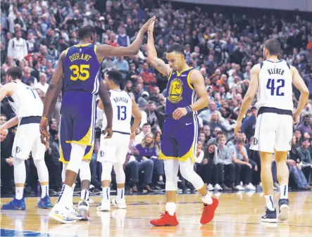  ?? Richard W. Rodriguez / Associated Press ?? Kevin Durant high-fives teammate Stephen Curry near the end of the Warriors’ 119-114 victory over the Mavericks in Dallas.