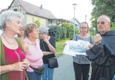  ?? FOTO: VERA ROMEU ?? Bruder Johannes (rechts), mit bürgerlich­em Namen Erich Fischer, zeigt den Teilnehmer­n der historisch­en Führung ein alte Karte des Wilhelmite­rKlosters.