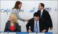  ?? PROVIDED TO CHINA DAILY ?? Caroline Beteta (left, standing), president and CEO of Visit California, shakes hands with Guo Jianye, director general of the Commercial Steering Committee at China Southern Airlines, while Leona Reed (left, front), associate vice-president of Global...