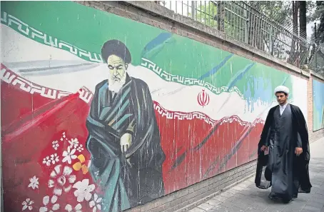  ?? Picture: Getty Images. ?? A man passes a mural painted on the wall of the former US Embassy in Tehran.